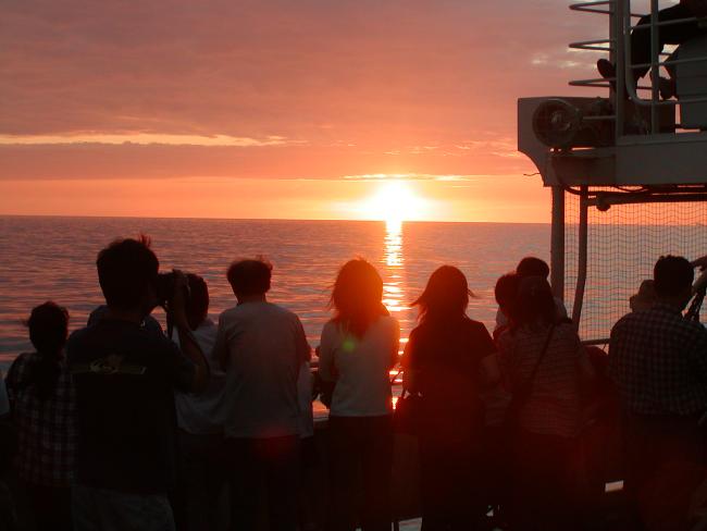 夏の日本海に沈む夕日を船上から楽しむ