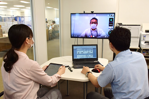業務中の様子(タブレット端末を手に、オンライン会議を行っている)